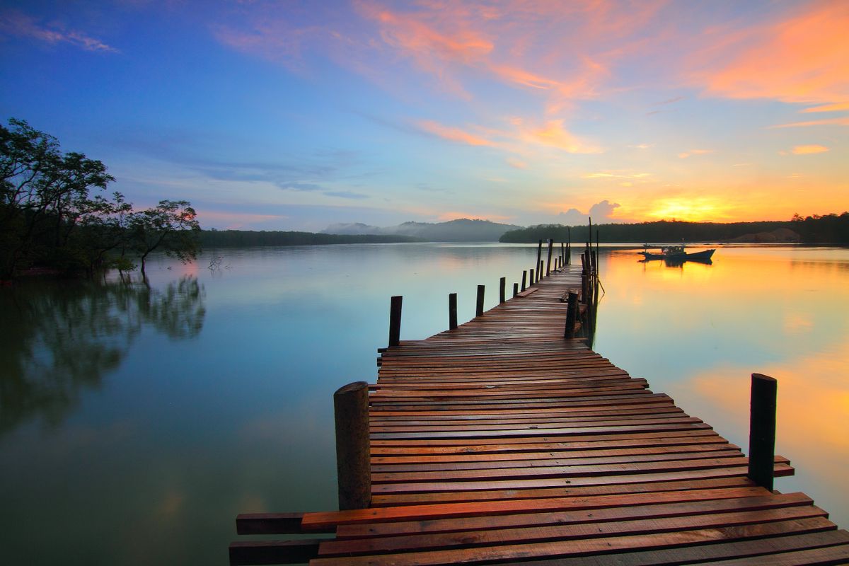 A wooden jetty stretching over calm water at sunrise